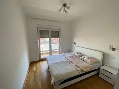 a white bedroom with a bed and a window at Apartments City Life in Podgorica