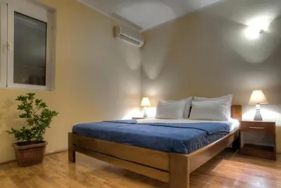 a bedroom with a bed with blue sheets and two lamps at Castellamare Residence in Petrovac na Moru