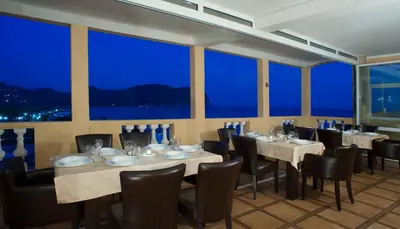 a restaurant with tables and chairs and large windows at Castellamare Residence in Petrovac na Moru