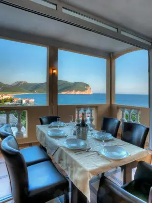 a dining room with a table and chairs and the ocean at Castellamare Residence in Petrovac na Moru
