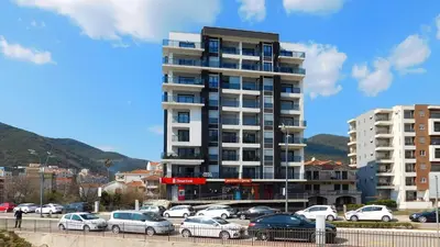 a tall building with cars parked in a parking lot at Sea View Apartments Perovic in Budva
