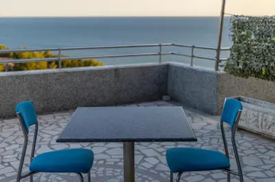 a table and chairs on a balcony with the ocean at Blue Sky Apartments-Ulcinj, Montenegro in Ulcinj