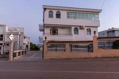 a white house with a fence in front of a street at Blue Sky Apartments-Ulcinj, Montenegro in Ulcinj