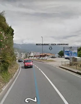 a red car driving down a road with a bike lane at Apartmani Cupic in Budva