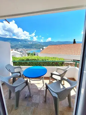 a balcony with chairs and a blue table and chairs at Apartmani Cupic in Budva
