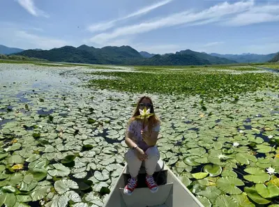 a woman sitting on a boat in a body of water at Skadar lake Apartments Pajovic in Virpazar
