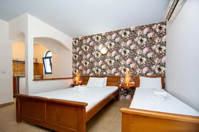 two beds in a room with a floral wallpaper at Tanja Apartments in Rafailovici