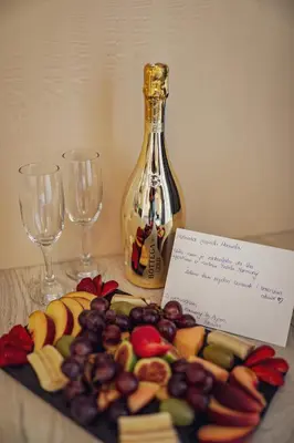 a plate of fruit and wine glasses and a bottle at Hotel Harmony by Aycon in Petrovac na Moru