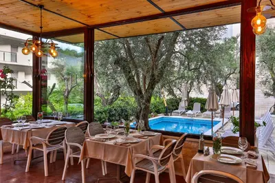 a dining room with tables and chairs and a pool at Hotel Harmony by Aycon in Petrovac na Moru