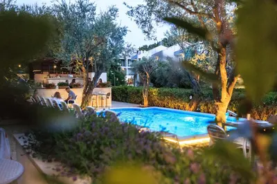 a swimming pool in a yard with chairs and trees at Hotel Harmony by Aycon in Petrovac na Moru
