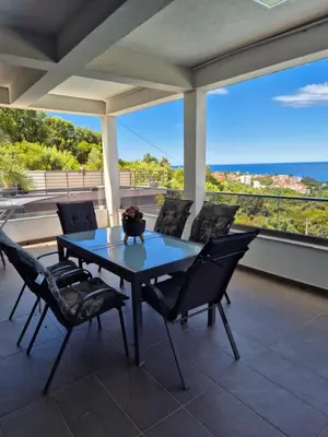 a table and chairs on a patio with a view of the ocean at Apartments Merin in Utjeha