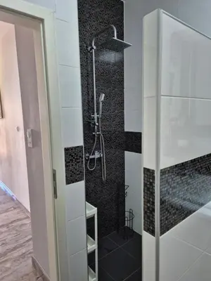 a bathroom with a shower with black and white tiles at Apartments Merin in Utjeha