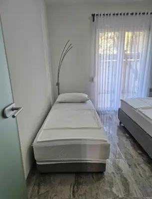 a room with two beds in it with a window at Apartments Merin in Utjeha