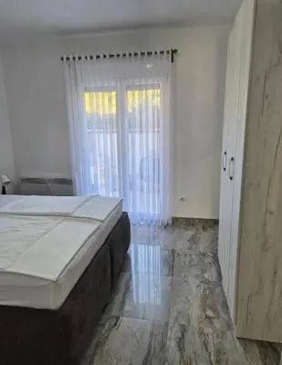 a bedroom with a bed and a sliding glass door at Apartments Merin in Utjeha
