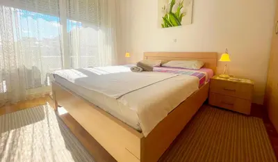a bed in a room with a large window at Andrey Apartment in Budva