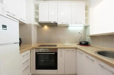 a white kitchen with white cabinets and a sink at Andrey Apartment in Budva