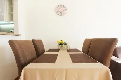 a table with brown chairs and a table with flowers on it at Andrey Apartment in Budva