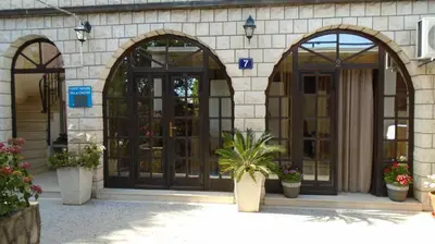 a building with three doors and a plant in front at Guest house Villa Castio in Petrovac na Moru