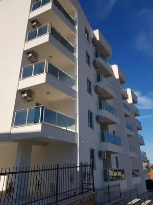 a white apartment building with balconies and a fence at Apartment Melina in Dobra Voda