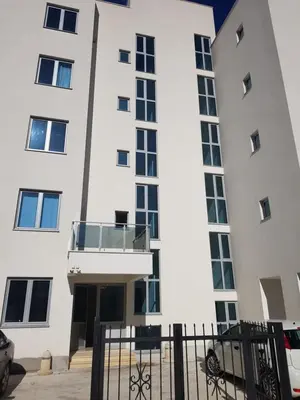 a white building with a balcony in front of it at Apartment Melina in Dobra Voda