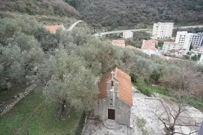a small building on a hill with trees and buildings at Anja Apartment in Rafailovici