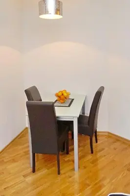 a table with chairs and a bowl of fruit on it at Anja Apartment in Rafailovici