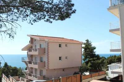 a building on a hill with the ocean in the background at Vila POGLED in Bar