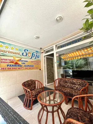 a patio with chairs and a table and a sign at Apartments Sofija in Budva