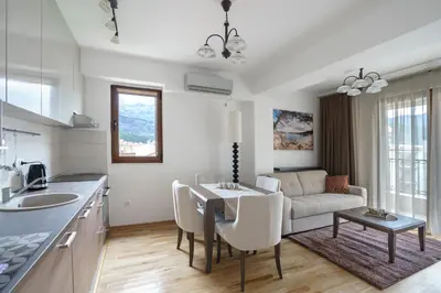 a kitchen and living room with a table and a couch at Apartments LORA Jadranskij put in Budva