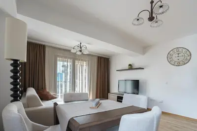 a white living room with a table and a couch at Apartments LORA Jadranskij put in Budva