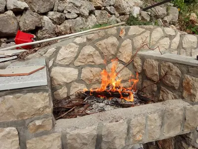 a fire burns in a stone fire pit at Holiday Home Free your mind in Dobra Voda