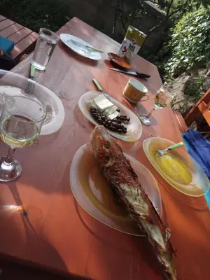 a table with a fish on a plate with a glass of wine at Holiday Home Free your mind in Dobra Voda