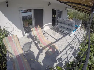 two deck chairs and a bench on a patio at Holiday Home Free your mind in Dobra Voda