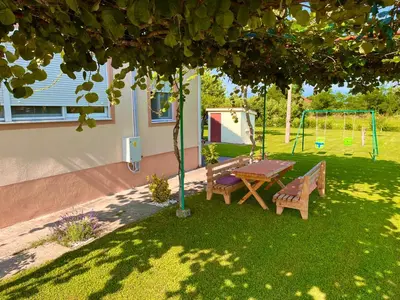 a picnic table and swing under a tree in a yard at Apartment Helena Airport in Podgorica