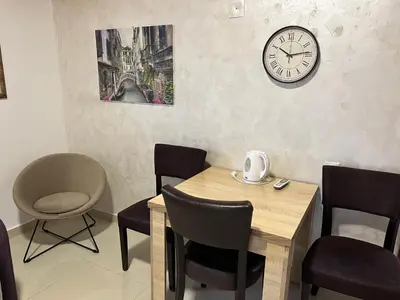 a dining room with a table and a clock on the wall at Apartment Helena Airport in Podgorica