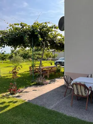 a table and chairs in a park with a picnic bench at Apartment Helena Airport in Podgorica