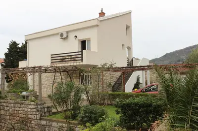 a white house with a fence in front of it at Apartment Dijana in Petrovac na Moru