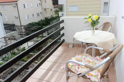 a balcony with a table and chairs and a vase of flowers at Apartment Dijana in Petrovac na Moru