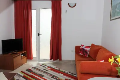 a living room with an orange couch and a television at Apartment Dijana in Petrovac na Moru