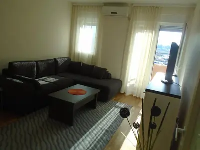 a living room with a black couch and a table at Fantastic brand new apartment in Podgorica