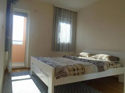 a bedroom with a large bed with a window at Fantastic brand new apartment in Podgorica