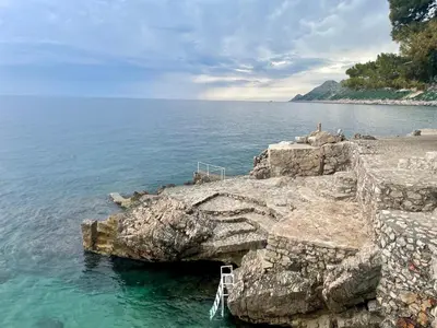 a ladder sticking out of a rock formation in the water at Apartments & Rooms Elite in Dobra Voda