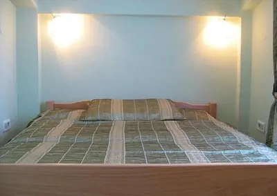 a bed in a bedroom with two lights on the wall at Apartments & Rooms Elite in Dobra Voda
