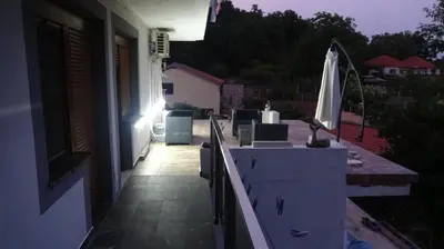 an outdoor patio with an umbrella on a house at Apartment Kraljica Jelena in Virpazar