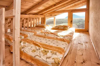 two beds in a wooden room with a large window at Accommodation 