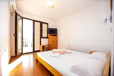 a bedroom with a white bed and a large window at Villa Vojnic in Budva