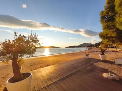 a wooden deck with trees on a beach at Studio apartman na plaži in Rafailovici