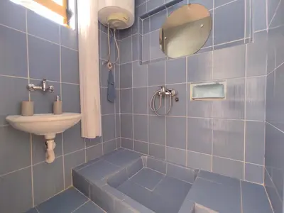 a blue tiled bathroom with a sink and a mirror at Studio apartman na plaži in Rafailovici
