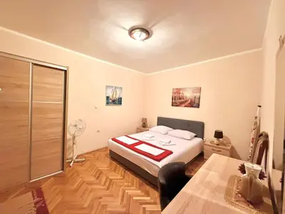 a bedroom with a bed and a table and a fan at Beachfront Apartments Oaza 1 in Petrovac na Moru