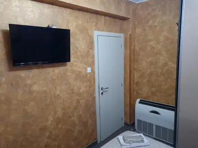 a room with a toilet and a television on the wall at Apartman Centar Lux in Budva
